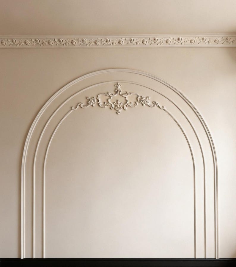 K&ouml;nnte beinhalten: Eine beige Wand mit einem bogenf&ouml;rmigen Stuckdesign und einem zentralen Zierornament aus Gips. Die Wand verf&uuml;gt oben &uuml;ber eine horizontale Deckenleiste mit wiederkehrendem Blumenmuster und unten &uuml;ber eine schwarze Sockelleiste.