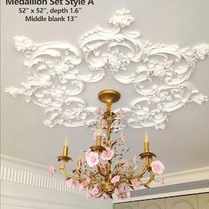 May include: A white, ornate ceiling medallion with floral and scroll designs, measuring 132 cm x 132 cm with a depth of 4 cm. A gold chandelier with pink flower accents hangs below. The text "Medallion Set Style A" is visible.