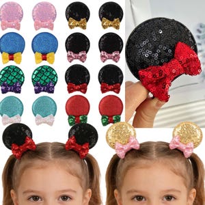 Puede incluir: Una colección de pinzas para el pelo con orejas de ratón con lentejuelas en varios colores, incluyendo rosa, azul, verde, rojo y dorado. Cada pinza tiene un lazo. Dos niños llevan las pinzas en la parte inferior de la imagen.