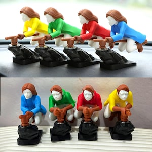 May include: A collection of colorful figurines depicting a person operating a lever. The figurines are in yellow, green, red, and blue outfits, with brown hair and white faces. Each figure is mounted on a black base.
