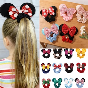 May include: A collection of colorful scrunchies and headbands with mouse ear designs. The scrunchies feature various bow styles, including polka dots, sequins, and plaid patterns. The ears are black and the bows are red, pink, and blue.