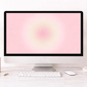 May include: A modern computer monitor with a pink and yellow gradient screen sits on a white desk. The desk is accessorized with a white keyboard, mouse, and decorative items, including flowers in a vase and pencils.
