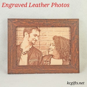 Pode incluir: Uma fotografia de um casal gravada em couro emoldurada. A fotografia est&aacute; em uma moldura de madeira marrom e mostra um homem e uma mulher olhando um para o outro. O fundo da fotografia &eacute; uma parede de tijolos.