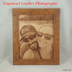 Pode incluir: Uma fotografia emoldurada de um casal, um homem e uma mulher, sorrindo para a c&acirc;mera. O homem est&aacute; usando um bon&eacute; de beisebol com um design de bandeira americana e &oacute;culos de sol. A mulher est&aacute; usando &oacute;culos de sol. A fotografia &eacute; gravada em um peda&ccedil;o de couro e emoldurada em uma moldura de madeira r&uacute;stica.