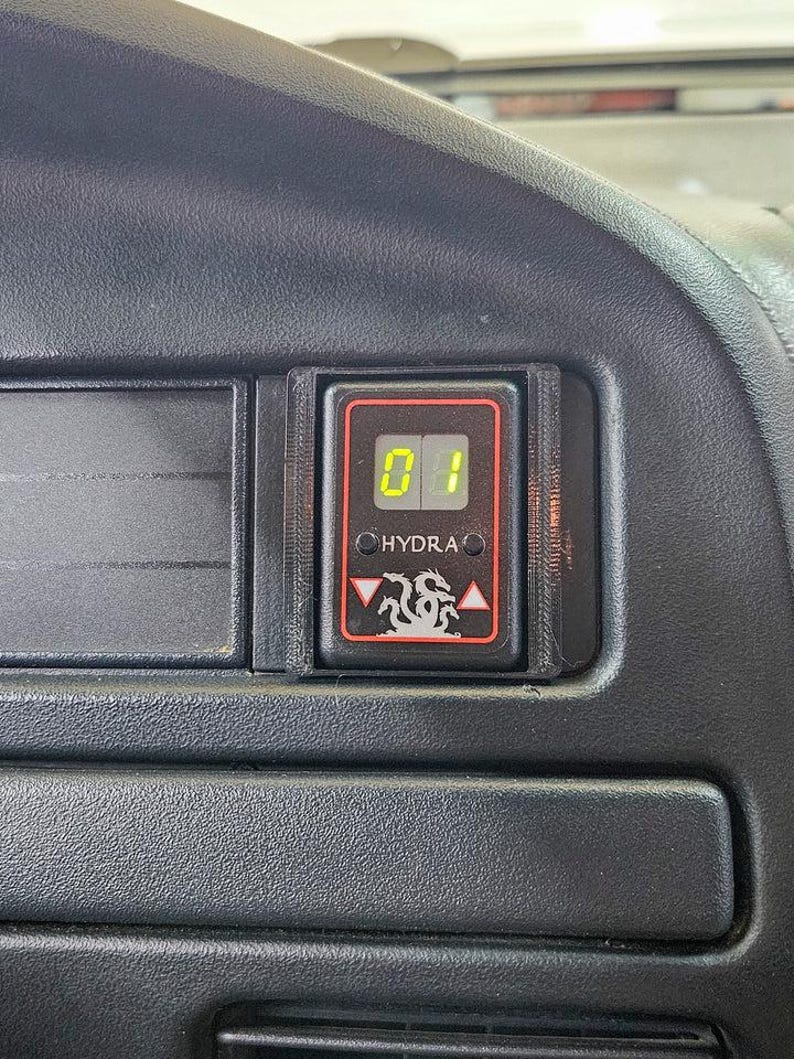 May include: A black dashboard with a digital display showing the number "01" in green. The display is framed in a black housing with the word "HYDRA" and a dragon logo. The dashboard has a textured surface.