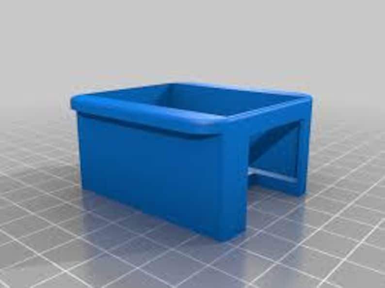 May include: A solid blue, rectangular 3D-printed object with a curved top edge and an open bottom. The object has a hollow interior and is set against a grid background.