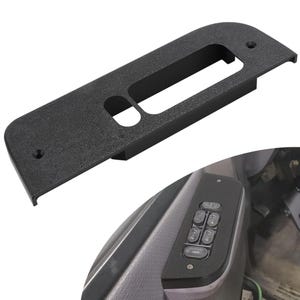 Puede incluir: Embellecedor de panel de puerta de coche de plástico negro con recortes para los controles de ventanas y cerraduras. El embellecedor tiene una superficie texturizada y dos orificios de montaje. La imagen también muestra el panel de control instalado con botones de ventana y cerradura.