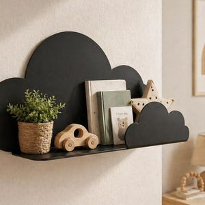 Peut inclure: Étagère noire en forme de nuage fixée au mur blanc, avec une petite plante en pot, une voiture en bois, des livres et une décoration en forme d'étoile. Un cadre avec un arc-en-ciel est accroché au mur. Solution de rangement décorative.