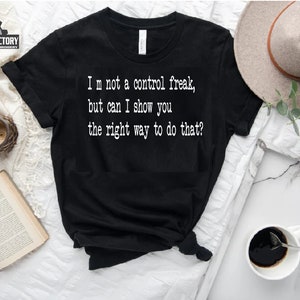 Könnte beinhalten: Schwarzes T-Shirt mit weißem Text, der lautet: "Ich bin kein Kontrollfreak, aber kann ich dir zeigen, wie man das richtig macht?"
