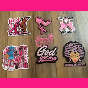 May include: Six embroidered patches featuring breast cancer awareness themes. Designs include a high heel, a pink ribbon, sneakers, and text such as find a cure, she fought she won, God got me, and stronger than cancer, with a central Sparkle Society logo.