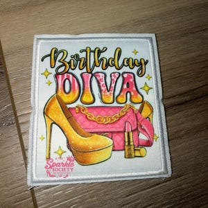 May include: A rectangular fabric patch featuring the text Birthday DIVA in yellow and pink gradient lettering. The design includes a yellow high-heeled platform shoe, a pink quilted handbag with a gold chain, and a lipstick tube, with Sparkle SOCIETY text.