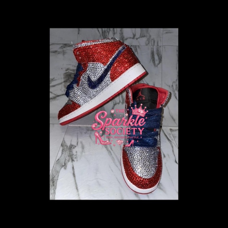 Puede incluir: Un par de zapatillas altas rojas, plateadas y azules. Las zapatillas est&aacute;n cubiertas de adornos brillantes. El logo de Nike es azul. Las suelas son blancas con un ribete rojo. La leng&uuml;eta del zapato es roja con la palabra "AIR" impresa.