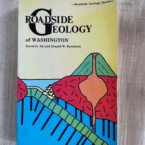 May include: A book cover with a colorful illustration of a volcano erupting. The book title is "Roadside Geology of Washington" by David D. Alt and Donald W. Hyndman. The book is part of the "Roadside Geology Series".