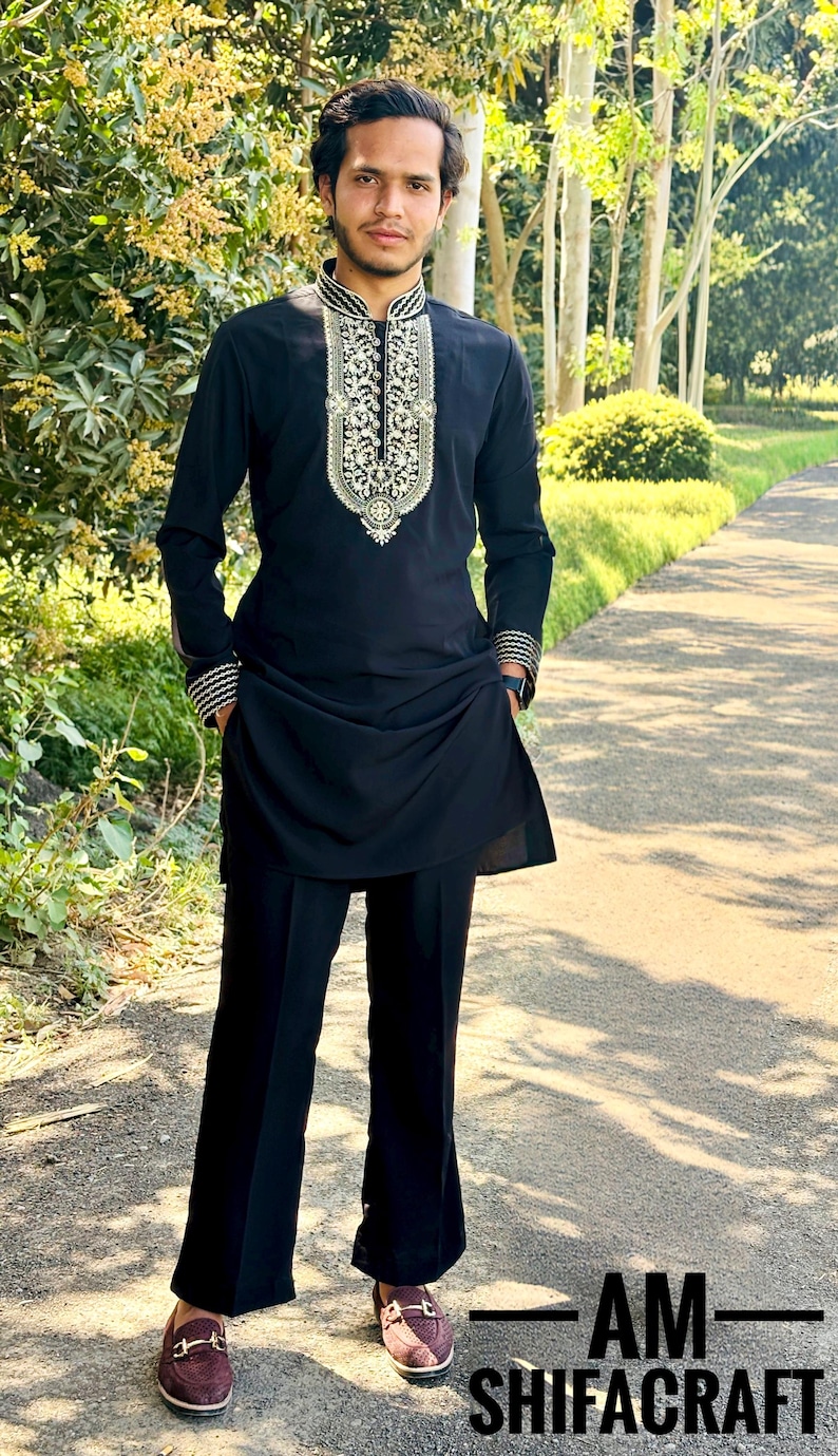 May include: Black kurta and matching pants with intricate white and gold embroidery on the collar and cuffs. The outfit is worn with burgundy loafers. The text "AM-SHIFACRAFT" is at the bottom of the image.