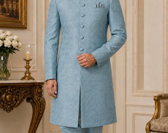Può includere: Uno sherwani azzurro con un sottile motivo geometrico, collo alla coreana e chiusura frontale con bottoni. La giacca a maniche lunghe è abbinata a pantaloni azzurri coordinati e mocassini azzurri, creando un completo uniforme.