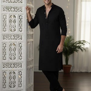 May include: Black kurta pajama set with intricate embroidery. The long-sleeved kurta features a mandarin collar and button-down front. The matching pajama pants complete the ensemble. The text "AM SHIFACRAFTDESIGN" is visible.