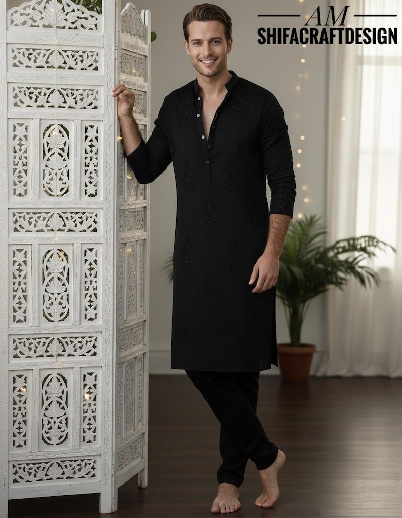 May include: Black kurta pajama set with intricate embroidery. The long-sleeved kurta features a mandarin collar and button-down front. The matching pajama pants complete the ensemble. The text "AM SHIFACRAFTDESIGN" is visible.