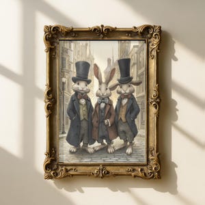 Könnte beinhalten: Ein gerahmter Druck mit drei anthropomorphen Kaninchen in formeller Kleidung, darunter Zylinder und Mäntel, die auf einer Kopfsteinpflasterstraße stehen. Das Kunstwerk hat eine Vintage-Ästhetik mit einem goldenen, verzierten Rahmen und einem Stadt-Hintergrund.