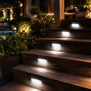 May include: Wooden outdoor staircase with integrated, bright white LED step lights. The rectangular lights are flush-mounted, illuminating each step. The wood has a dark brown tone, and the scene is set at dusk.