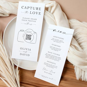 May include: Two white wedding signs with black text. One sign reads "CAPTURE the LOVE" and includes a camera graphic with a QR code. The other sign is a menu with appetizers, starters, main course, and desserts. The names Olivia and David are on both signs.