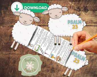 May include: A digital download featuring two cartoon sheep with the text "Psalm 23." The design includes a paper strip with Bible verses and illustrations. A hand is holding a pencil, writing on the paper strip. The background is a wooden surface.