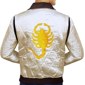 May include: Cream-colored satin jacket with a quilted pattern and a brown collar. The back of the jacket features a large, embroidered yellow scorpion design. The jacket has black accents on the sides.
