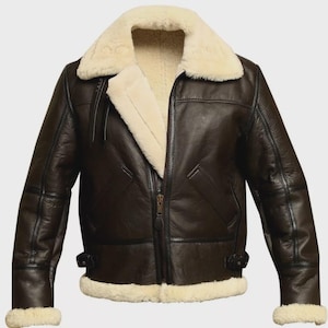May include: A brown leather jacket with a cream-colored shearling collar and lining. The jacket features a zipper closure, two front pockets, and shearling trim on the cuffs. The jacket has a classic aviator style.