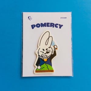 Könnte beinhalten: Ein Aufkleber mit einem Cartoon-Kaninchen, das ein Messer hält, mit dem Wort "POMERCY" über dem Bild. Der Aufkleber befindet sich auf einer weißen Karte mit einem blauen Logo und dem Wort "STICKER". Der Hintergrund ist einfarbig blau.