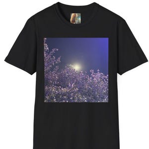 May include: Black t-shirt featuring a square image of a night sky with a bright moon and purple foliage. The image is centered on the front of the shirt. The t-shirt has short sleeves and a crew neck.