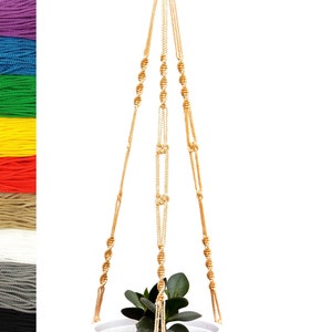 May include: A macrame plant hanger made of natural cotton rope. The hanger is in the shape of a triangle with a knotted design. The hanger is shown with a small plant in a white pot.