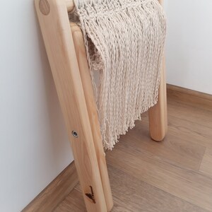 Op de afbeelding: Een houten kruk met een macram&eacute; zitting. De kruk is gemaakt van natuurlijk hout en heeft een eenvoudig ontwerp. De macram&eacute; zitting is gemaakt van wit katoenen koord en heeft een franje.
