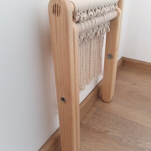 Op de afbeelding: Een houten kruk met een macram&eacute; zitting. De kruk is gemaakt van natuurlijk hout en heeft een eenvoudig ontwerp. De macram&eacute; zitting is gemaakt van natuurlijk katoenen touw en heeft een franje.
