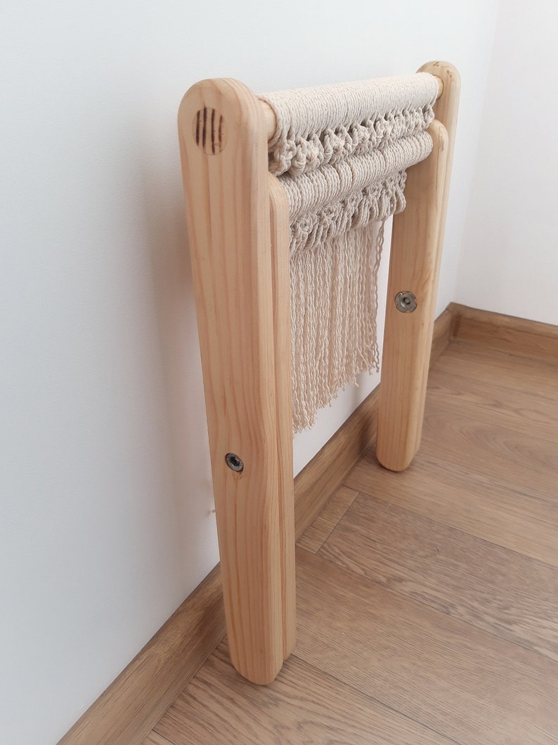 Op de afbeelding: Een houten kruk met een macram&eacute; zitting. De kruk is gemaakt van natuurlijk hout en heeft een eenvoudig ontwerp. De macram&eacute; zitting is gemaakt van natuurlijk katoenen touw en heeft een franje.