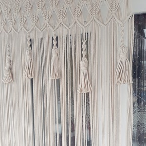 Puede incluir: Un tapiz de macram&eacute; blanco con un patr&oacute;n de diamante y borlas. El tapiz est&aacute; hecho de cord&oacute;n de algod&oacute;n y es un elemento de decoraci&oacute;n bohemia popular.