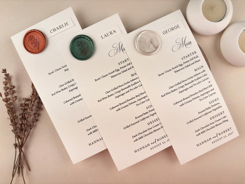May include: Elegant wedding menu cards with names like Charlie, Laura, and George, sealed with wax stamps. The menus feature a detailed dinner selection, including starters, main courses, sides, and dessert options. The event is dated August 21, 2027.