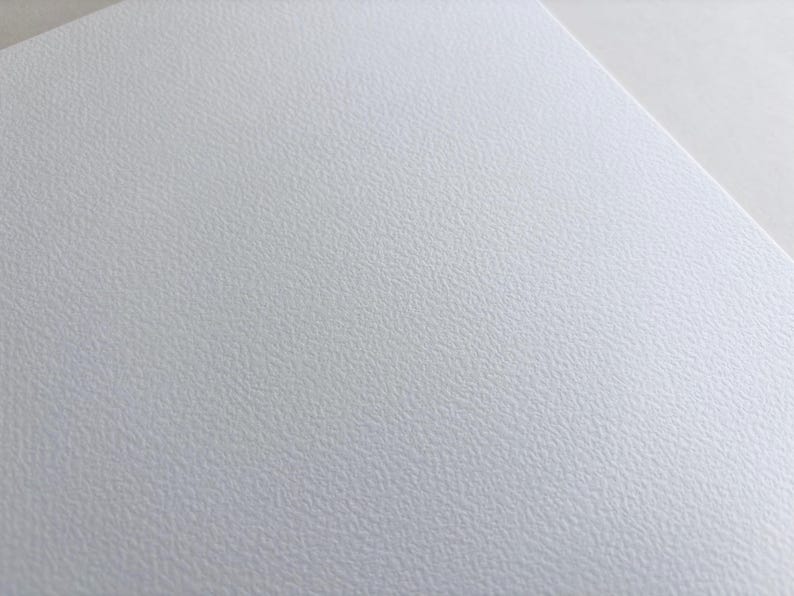 May include: Close-up of a textured white surface. The surface has a subtle, irregular pattern, creating a slightly rough appearance. The image is well-lit, highlighting the texture and the clean, neutral color.