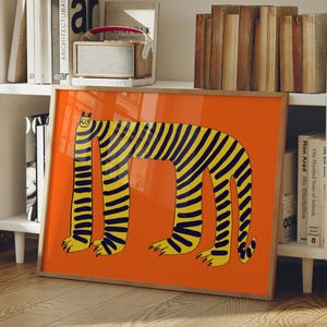 May include: A framed rectangular wall art print featuring a stylized illustration of a long-bodied, four-legged creature with yellow and black stripes on a solid orange background. The creature has a small head, elongated neck, and paws.