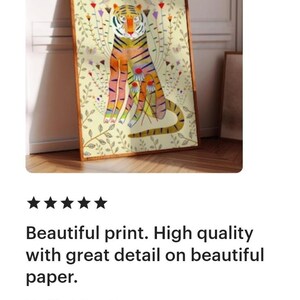 Puede incluir: Una l&aacute;mina de arte enmarcada rectangular que presenta un tigre estilizado en tonos naranja, amarillo y azul, rodeado de delicados tallos florales, hojas y peque&ntilde;os p&aacute;jaros sobre un fondo crema p&aacute;lido, en un marco de madera sencillo.