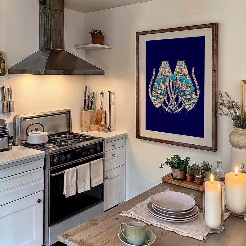Puede incluir: Una impresi&oacute;n enmarcada de dos leopardos estilizados con flores azules sobre un fondo azul oscuro. La impresi&oacute;n est&aacute; colgada en una pared blanca en un ambiente de cocina.