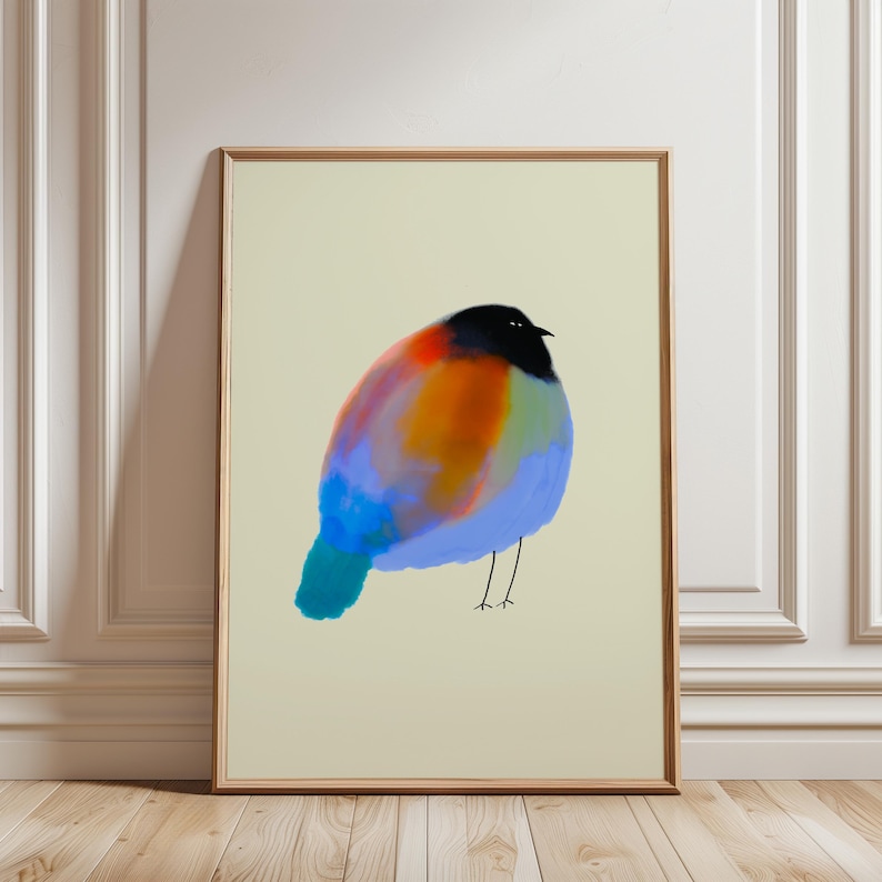 May include: A framed wall art print featuring a stylised, rounded bird illustration. The bird has a solid black head, a vibrant body with blended patches of orange, red, and blue, and thin, simple black lines representing its two legs.