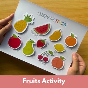 May include: A white educational activity sheet titled I KNOW THE fruits featuring colourful illustrations of a pineapple, watermelon, mango, apple, pear, strawberry, orange, lemon, cherry, and peach with their corresponding names printed below each fruit.