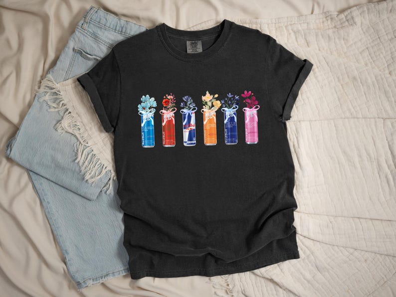 K&ouml;nnte beinhalten: Schwarzes T-Shirt mit einem farbenfrohen Blumendesign. Die Grafik zeigt sechs stilisierte Vasen, jede gef&uuml;llt mit verschiedenen Blumen und mit einem Band gebunden. Auf der linken Seite des Bildes ist eine hellblaue Jeans zu sehen.