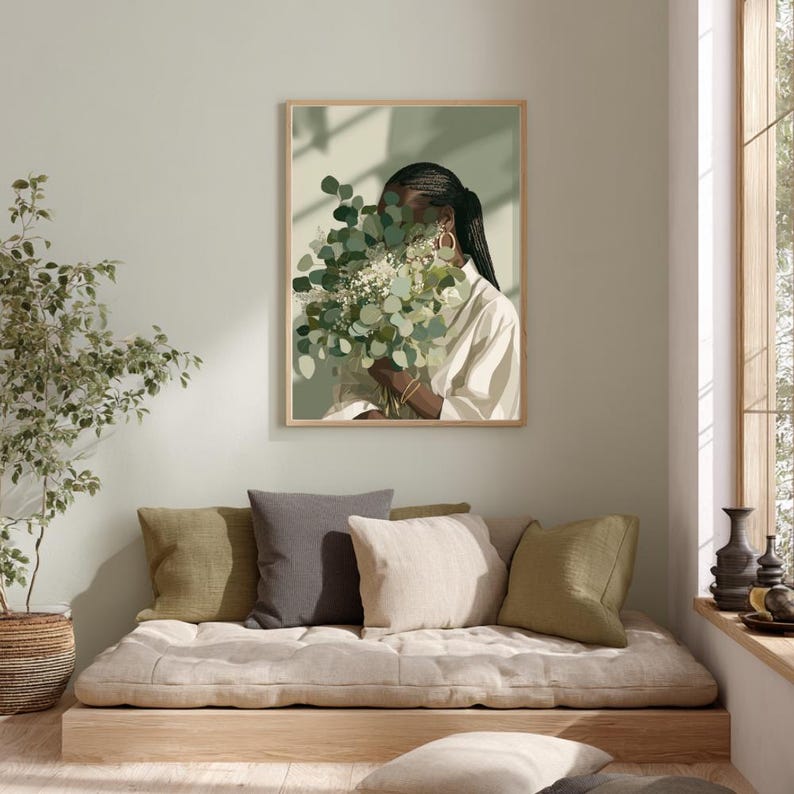 May include: A framed art print featuring a person holding a bouquet of green and white flowers. The person is wearing a white shirt and gold hoop earrings. The artwork has a neutral color palette and is displayed on a light green wall.
