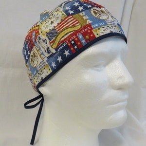 May include: A blue and white surgical scrub hat with a patriotic print featuring American flags, stars, and the words "Liberty and Justice for All".