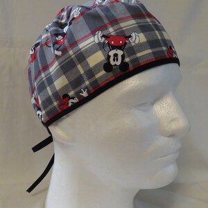 May include: A gray and white plaid scrub hat with a black trim and a Mickey Mouse print. The hat has black ties.