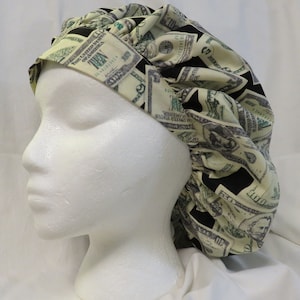 May include: A black and white satin sleep cap with a pattern of US dollar bills. The cap is gathered at the top and has a wide elastic band.