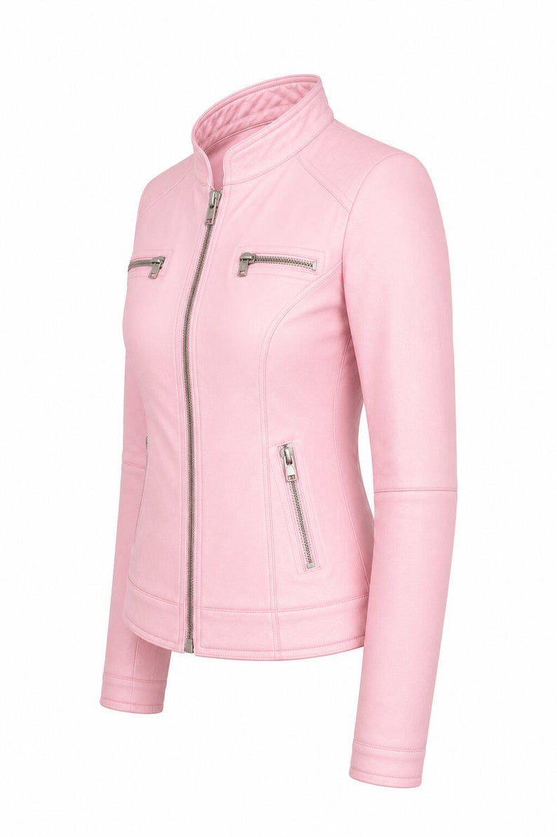 Puede incluir: Una chaqueta de color rosa claro con cuello alzado, una cremallera frontal plateada de longitud completa y dos bolsillos horizontales con cremallera en el pecho. La prenda incluye dos bolsillos verticales con cremallera en la cintura.
