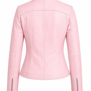 Puede incluir: Una chaqueta de color rosa claro con cuello alzado, mangas largas con pu&ntilde;os de cremallera plateados y detalles acolchados en los hombros. La parte posterior de la prenda presenta costuras verticales y un canes&uacute; horizontal en la parte superior.