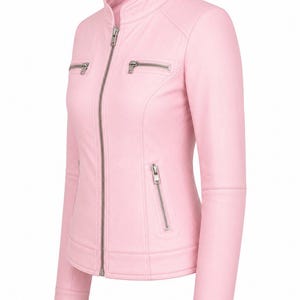 Puede incluir: Una chaqueta de color rosa claro con cuello alzado, una cremallera frontal plateada de longitud completa y dos bolsillos horizontales con cremallera en el pecho. La prenda incluye dos bolsillos verticales con cremallera en la cintura.