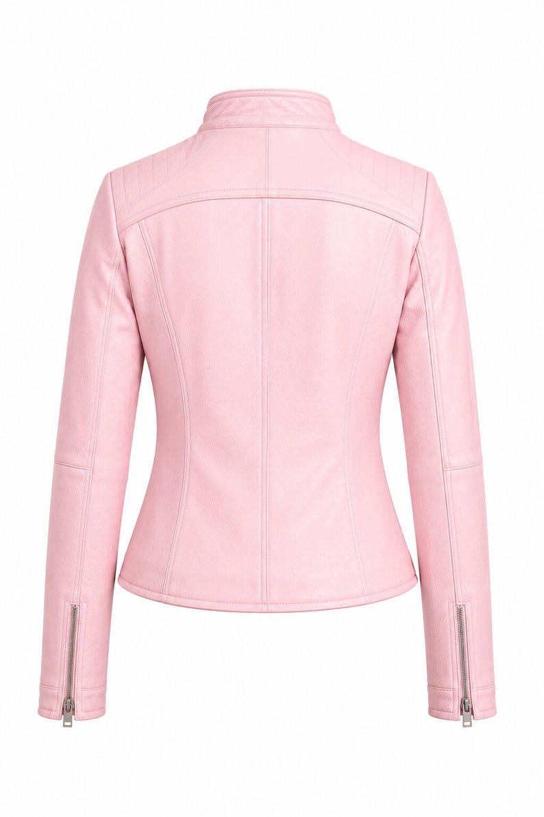 Puede incluir: Una chaqueta de color rosa claro con cuello alzado, mangas largas con pu&ntilde;os de cremallera plateados y detalles acolchados en los hombros. La parte posterior de la prenda presenta costuras verticales y un canes&uacute; horizontal en la parte superior.